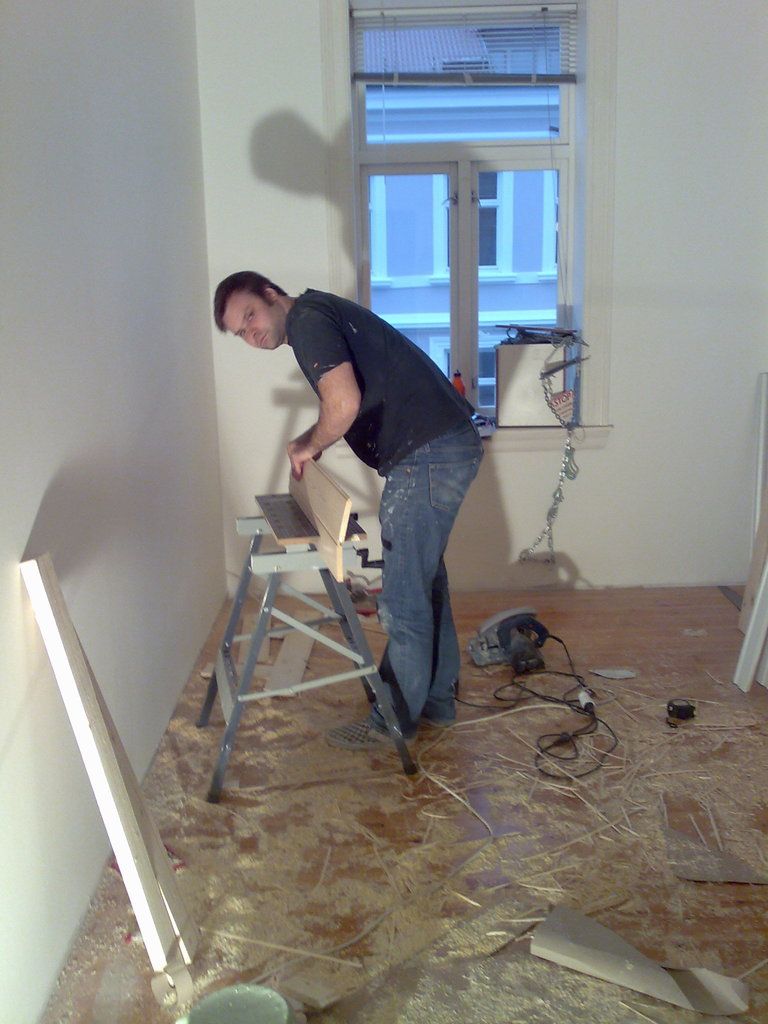 A carpenter cutting boards with a power saw in a room under renovation