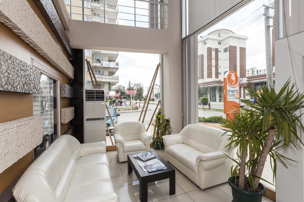 A bright double-height lounge with white leather sofas and tall glass walls