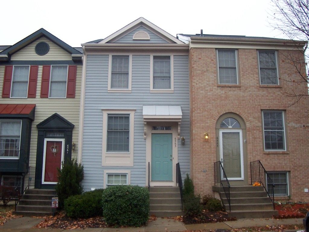A row of townhouses with red, blue and brick fronts and colourful front doors