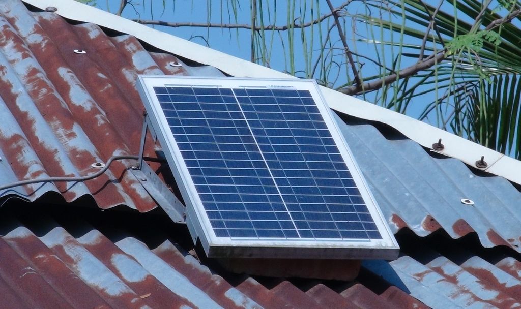 A solar panel fixed to a corrugated metal roof under a blue sky